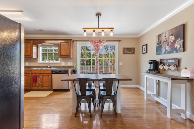 dining room featuring light wood-style floors, crown molding, visible vents, and baseboards