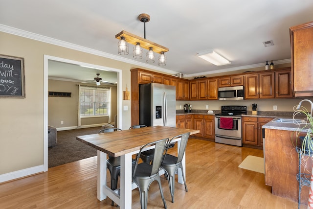kitchen featuring a sink, stainless steel appliances, brown cabinetry, visible vents, and ornamental molding