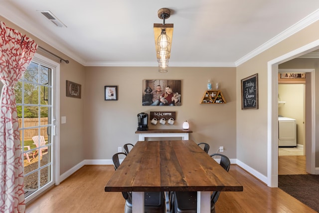 dining room featuring light wood-style flooring, washer / clothes dryer, visible vents, baseboards, and ornamental molding