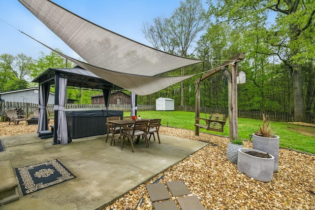 view of patio with a gazebo, a storage unit, a fenced backyard, and an outbuilding