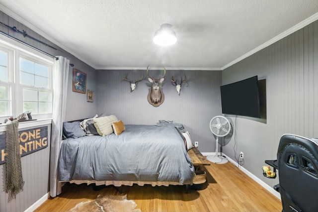bedroom with ornamental molding, wood finished floors, and a textured ceiling