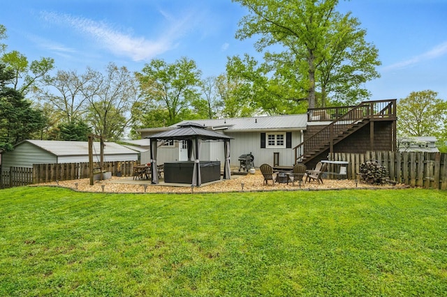rear view of house featuring a hot tub, a fenced backyard, an outdoor fire pit, a patio, and stairs