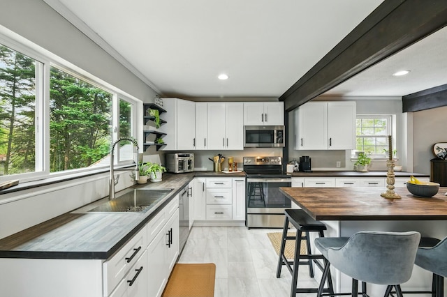 kitchen featuring open shelves, a sink, wood counters, stainless steel appliances, and marble finish floor