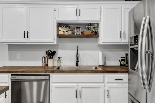 kitchen with butcher block counters, white cabinetry, sink, and appliances with stainless steel finishes