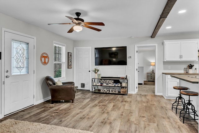 living room with beamed ceiling, ceiling fan, and light hardwood / wood-style floors