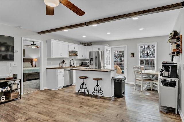 kitchen with a center island, light wood-type flooring, white cabinetry, and appliances with stainless steel finishes