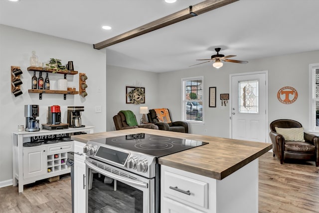 kitchen featuring butcher block counters, white cabinets, stainless steel range with electric stovetop, and light wood-type flooring