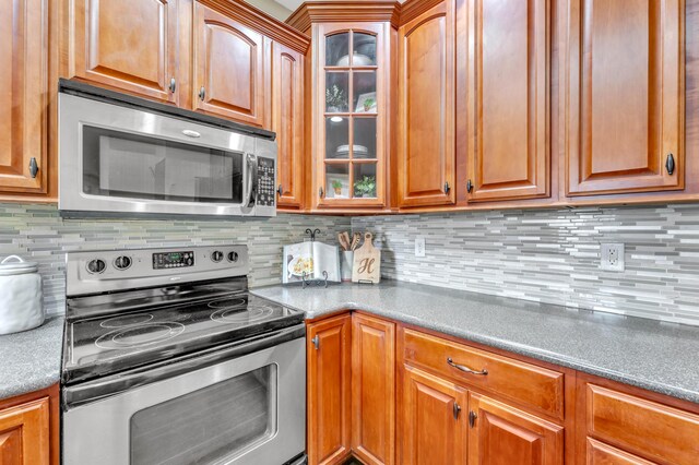 5414 Mandarin Cir, Hixson, TN 37343 - kitchen with appliances with stainless steel finishes, glass insert cabinets, tasteful backsplash, and brown cabinetry