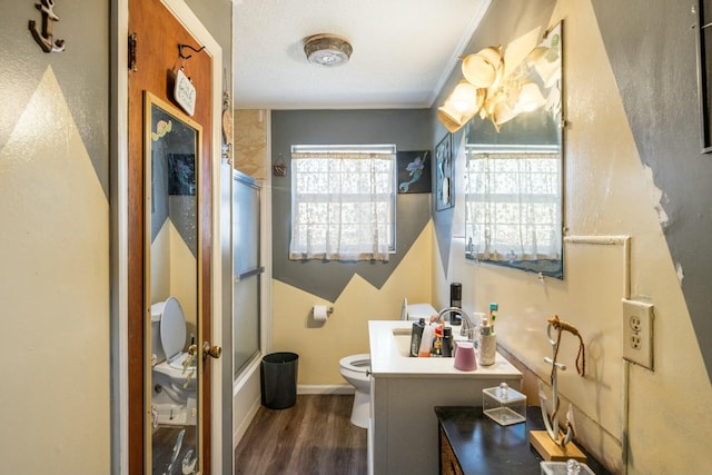 full bath with vanity, wood finished floors, baseboards, shower / bath combination with glass door, and toilet