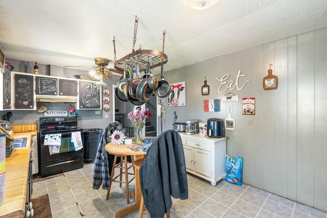 kitchen with light countertops, black electric range, under cabinet range hood, and a textured ceiling