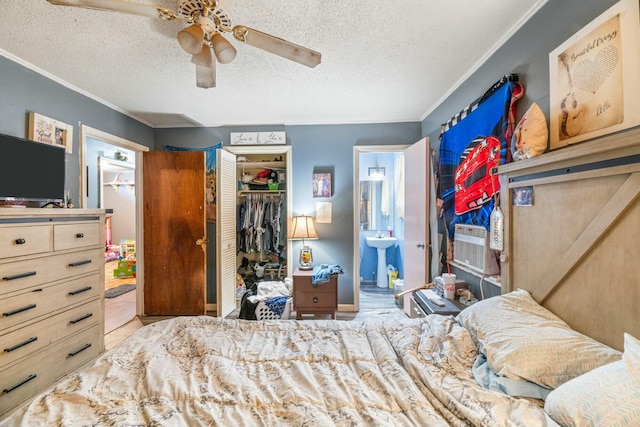 bedroom featuring a closet, ensuite bathroom, a textured ceiling, and crown molding