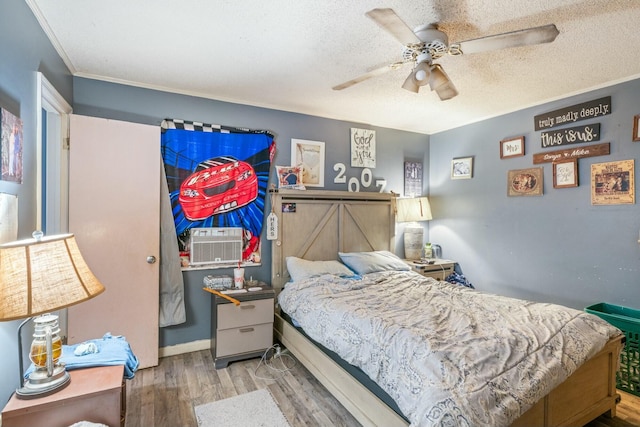 bedroom featuring ceiling fan, cooling unit, a textured ceiling, and wood finished floors