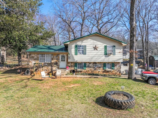 tri-level home with a front yard, stone siding, and metal roof