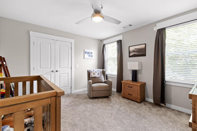 carpeted bedroom featuring ceiling fan, a closet, a crib, and multiple windows