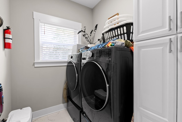 clothes washing area with cabinets and washer and dryer