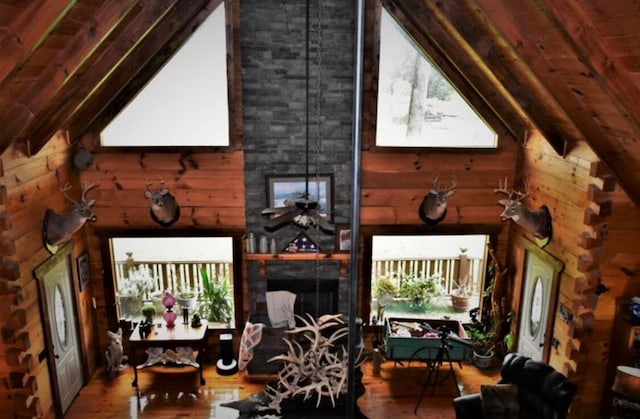 interior space featuring vaulted ceiling with beams, hardwood / wood-style flooring, a stone fireplace, and a healthy amount of sunlight