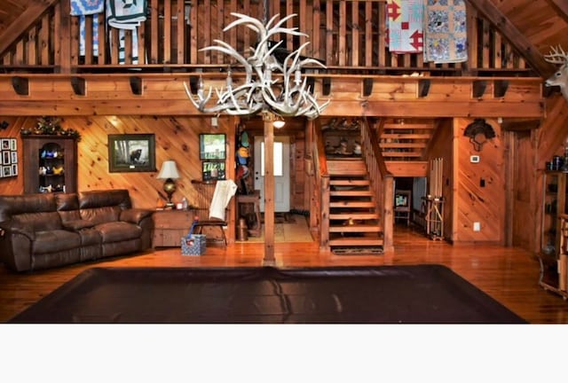 living room with wood walls, wood-type flooring, and vaulted ceiling