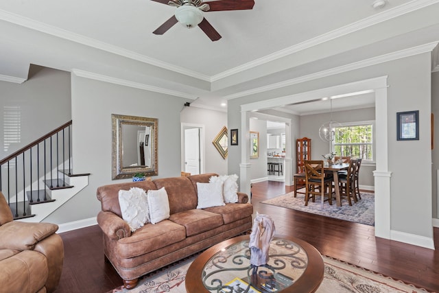 living area with baseboards, stairs, hardwood / wood-style flooring, and ceiling fan with notable chandelier