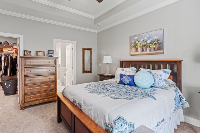 bedroom with a spacious closet, a raised ceiling, light carpet, a closet, and crown molding