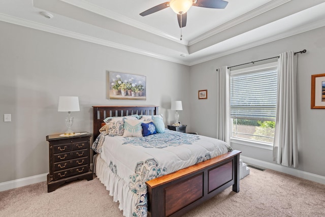 bedroom with a tray ceiling, ornamental molding, baseboards, and light carpet