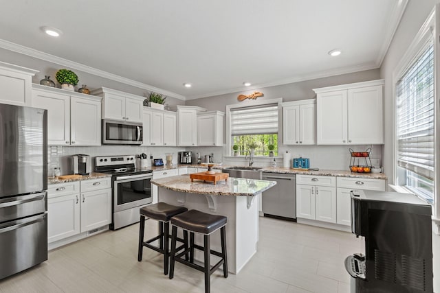 kitchen featuring decorative backsplash, appliances with stainless steel finishes, a breakfast bar, and white cabinetry