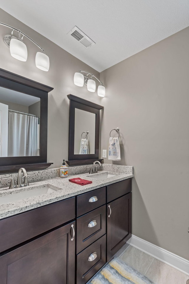 bathroom featuring double vanity, visible vents, tile patterned floors, and a sink