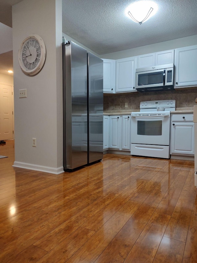 kitchen with stainless steel appliances, wood-type flooring, decorative backsplash, and white cabinets