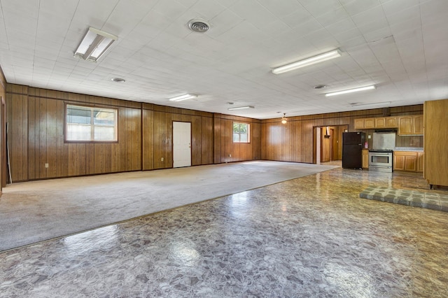 unfurnished room featuring wooden walls and a healthy amount of sunlight