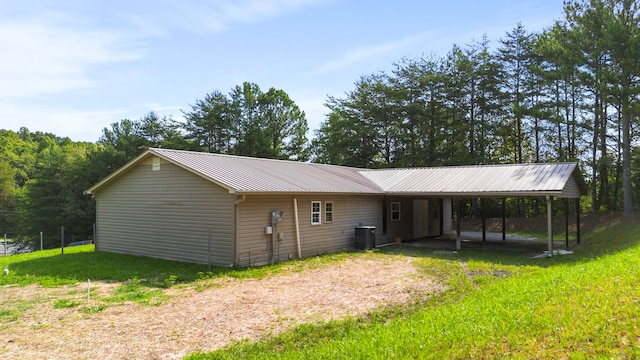 view of front of property with a front lawn, central AC unit, and a carport