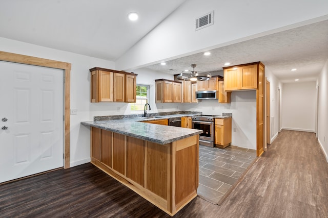 kitchen with sink, vaulted ceiling, dark hardwood / wood-style flooring, kitchen peninsula, and stainless steel appliances