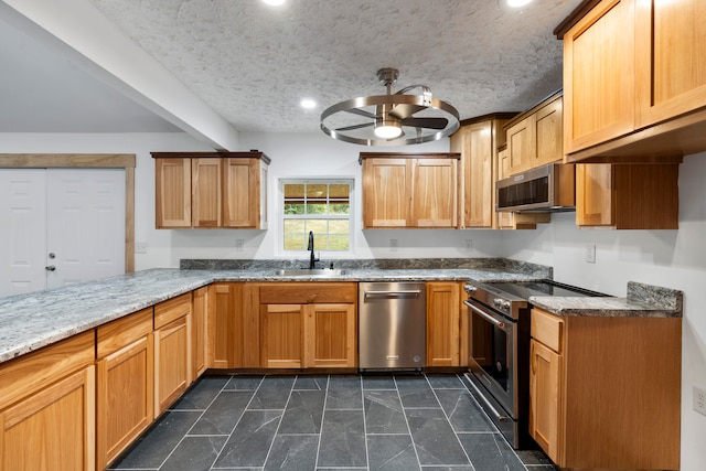 kitchen featuring sink, ceiling fan, a textured ceiling, appliances with stainless steel finishes, and light stone counters