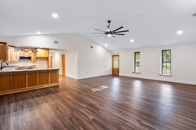 unfurnished living room featuring ceiling fan, sink, dark wood-type flooring, and vaulted ceiling