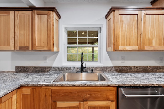 kitchen featuring dishwasher, light stone counters, and sink