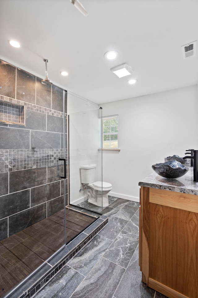 bathroom featuring vanity, toilet, and a shower with shower door