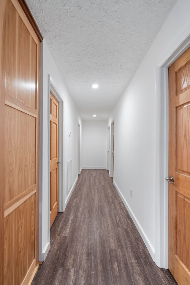 hallway featuring dark hardwood / wood-style flooring and a textured ceiling