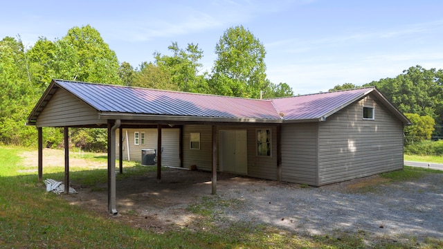 rear view of property with central AC and a carport