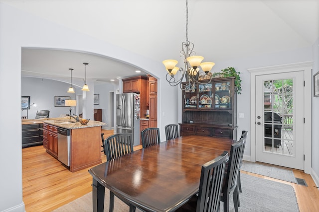dining room featuring a chandelier, light wood-style floors, arched walkways, and visible vents