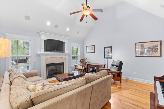 living area with recessed lighting, a ceiling fan, light wood-type flooring, a brick fireplace, and high vaulted ceiling