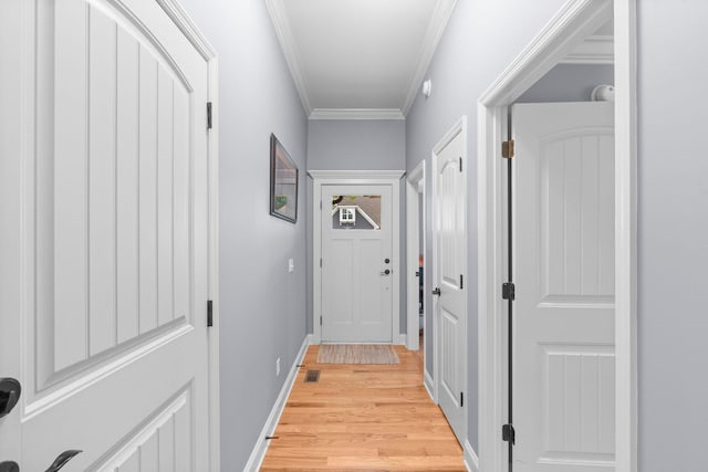 doorway to outside with crown molding, visible vents, light wood finished floors, and baseboards