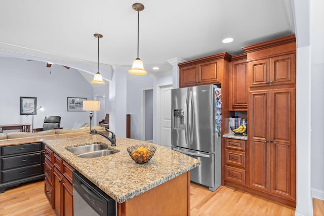 kitchen with light stone counters, a sink, light wood-style flooring, appliances with stainless steel finishes, and open floor plan