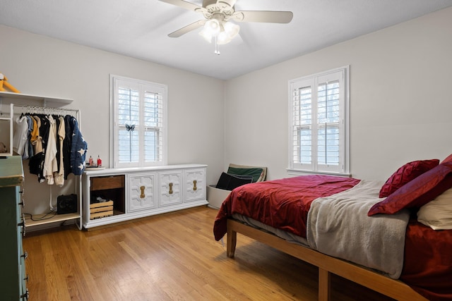 bedroom featuring a ceiling fan, multiple windows, and light wood-style floors