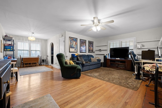 living room featuring ceiling fan, arched walkways, and wood finished floors