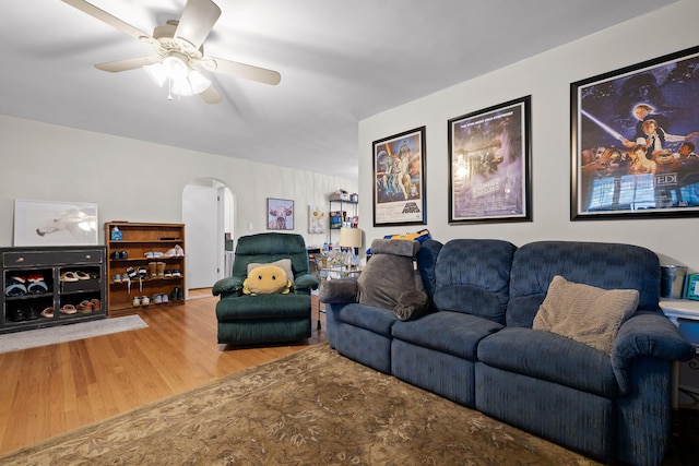 living area featuring arched walkways, ceiling fan, and wood finished floors