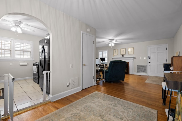 living room featuring light wood-style floors, visible vents, and ceiling fan