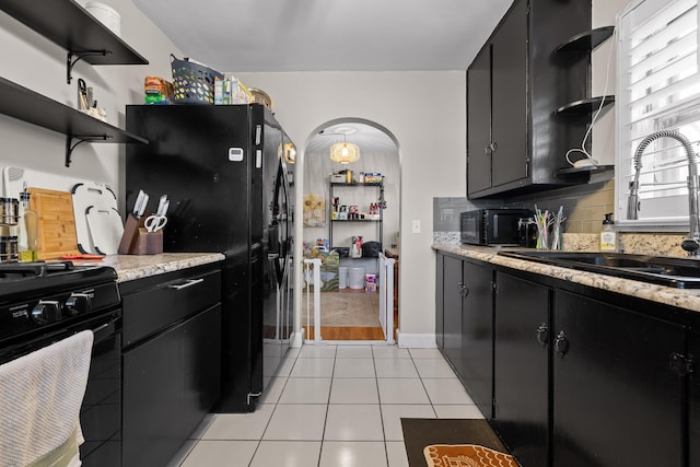 kitchen with open shelves, dark cabinetry, and a sink