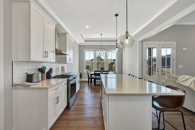 kitchen featuring hanging light fixtures, stainless steel range with gas cooktop, dark wood-type flooring, and a wealth of natural light