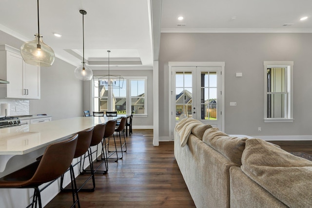 living room with dark hardwood / wood-style flooring, a tray ceiling, an inviting chandelier, and crown molding