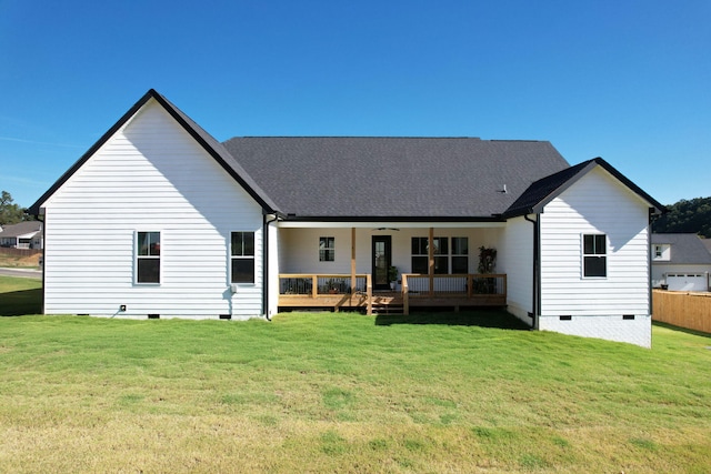 rear view of property with ceiling fan and a lawn