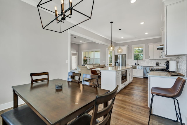 dining room with dark hardwood / wood-style floors, an inviting chandelier, ornamental molding, and sink