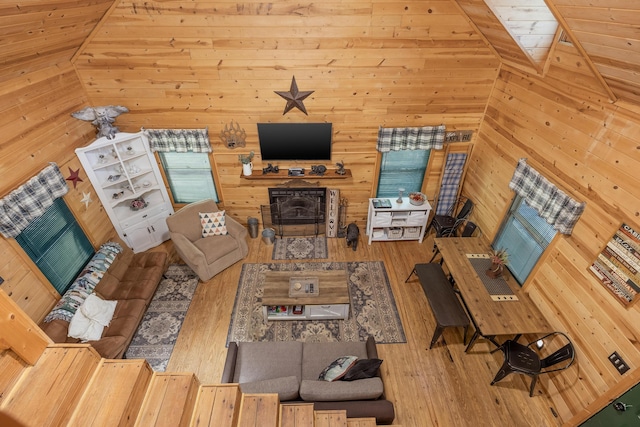 unfurnished living room featuring lofted ceiling, hardwood / wood-style flooring, and wooden walls